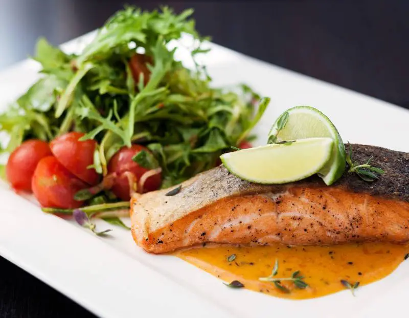 A plate of food with salmon and salad.